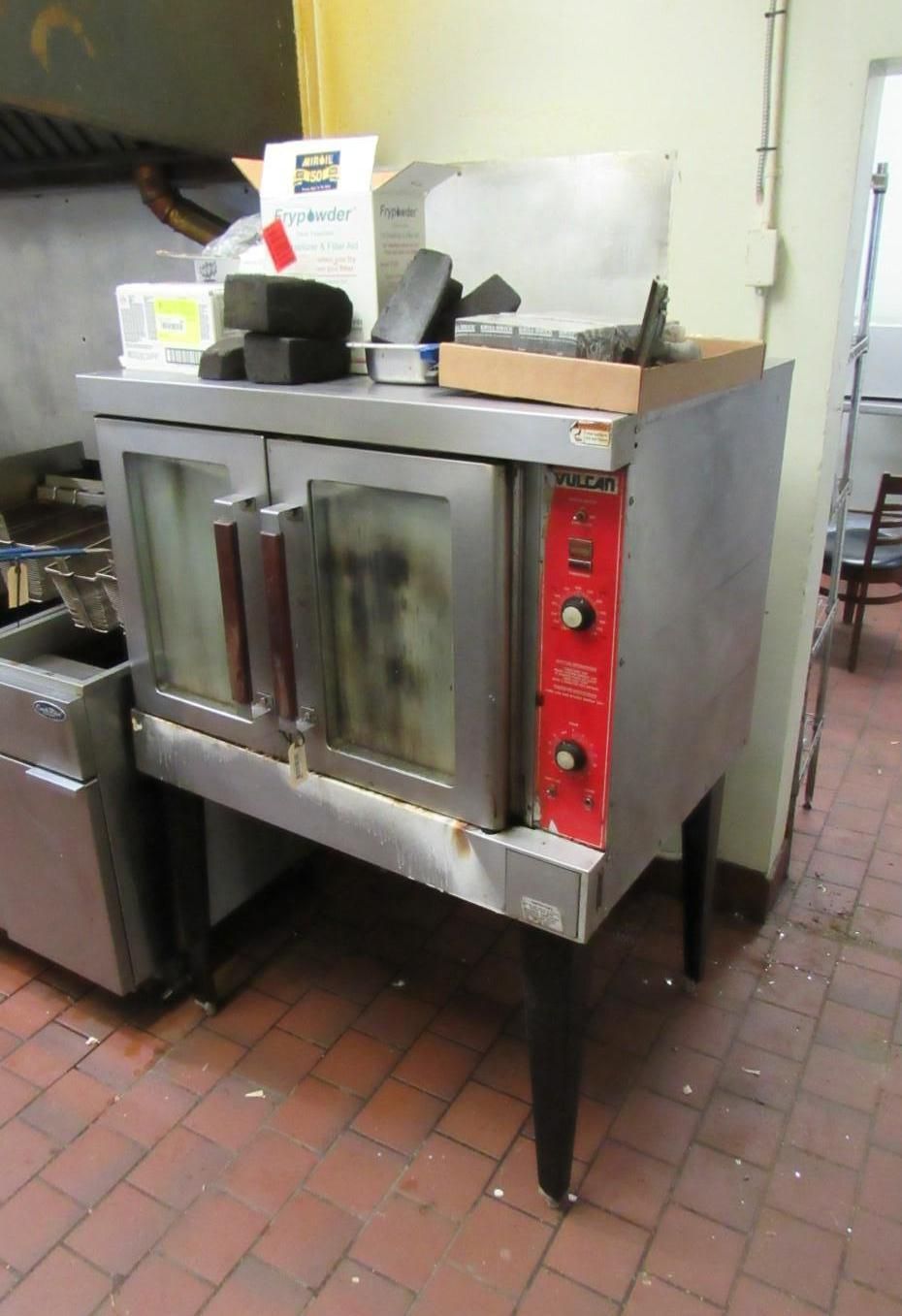 Stainless steel commercial oven with red control panel, in a commercial kitchen.