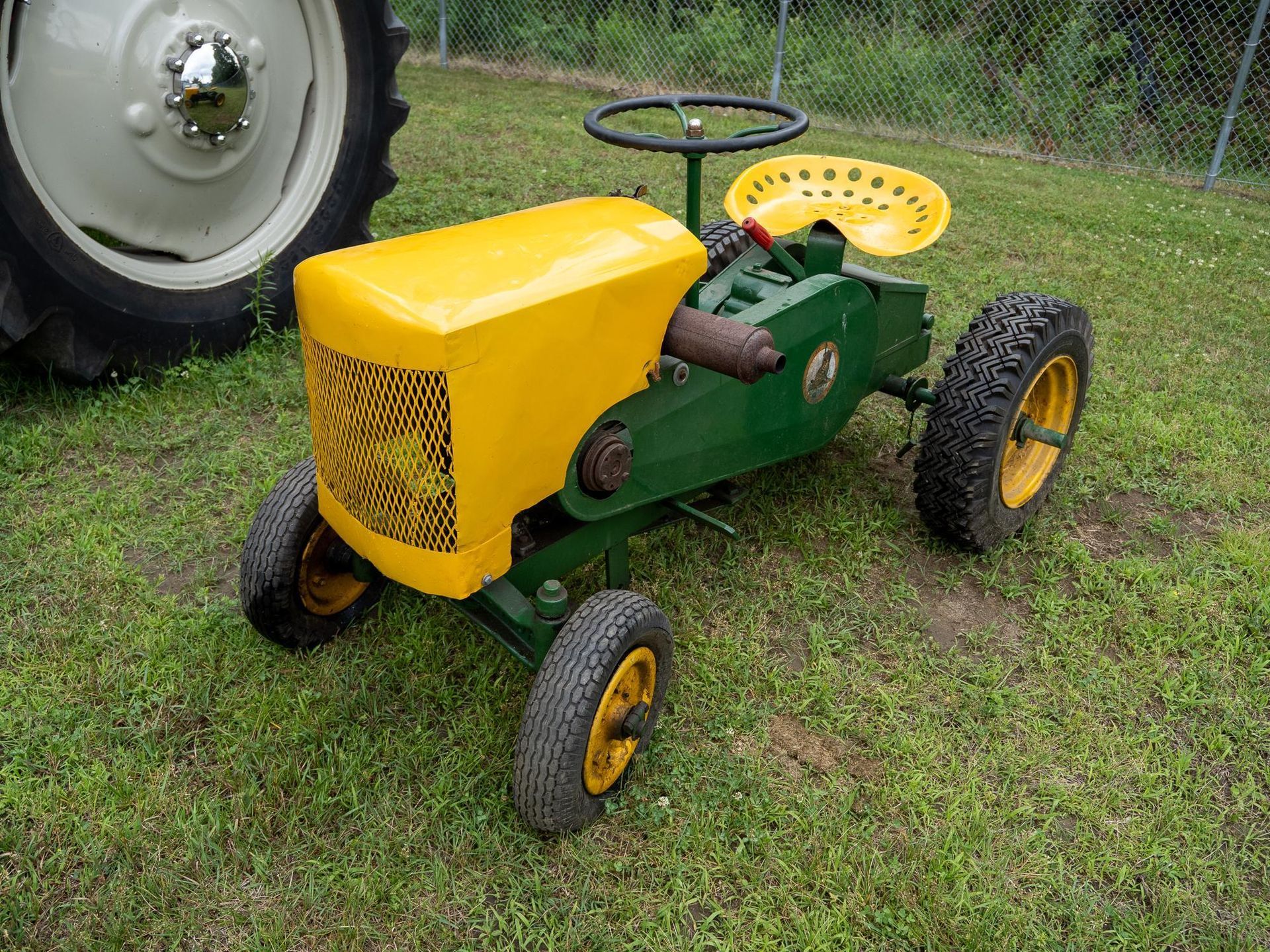 Yellow and green toy tractor on grass.