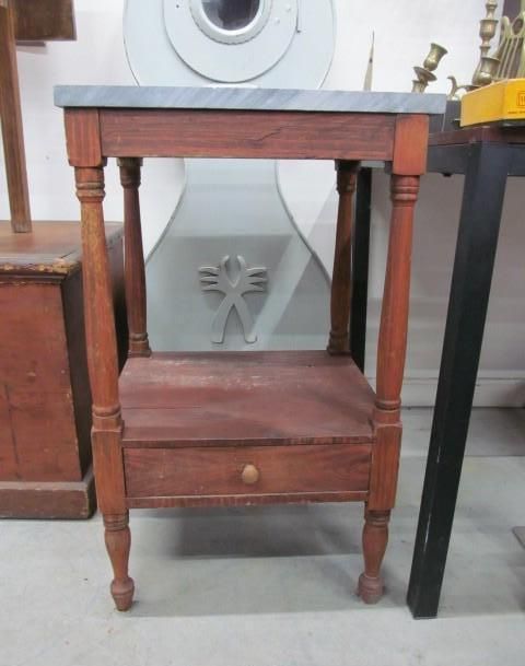 Wooden side table with a gray top, drawer, and turned legs.