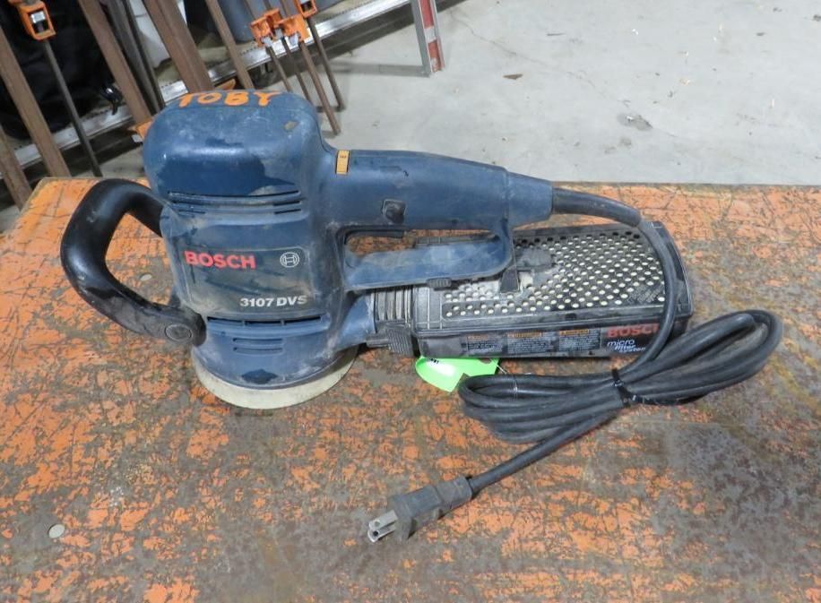 Blue Bosch sander on a brown work surface.