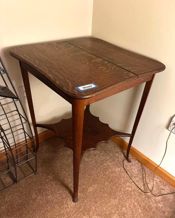 Brown wooden side table with a shelf, against a wall.