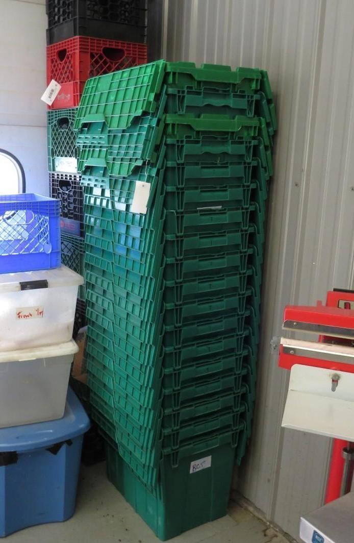 Tall stack of green plastic storage bins inside a room.