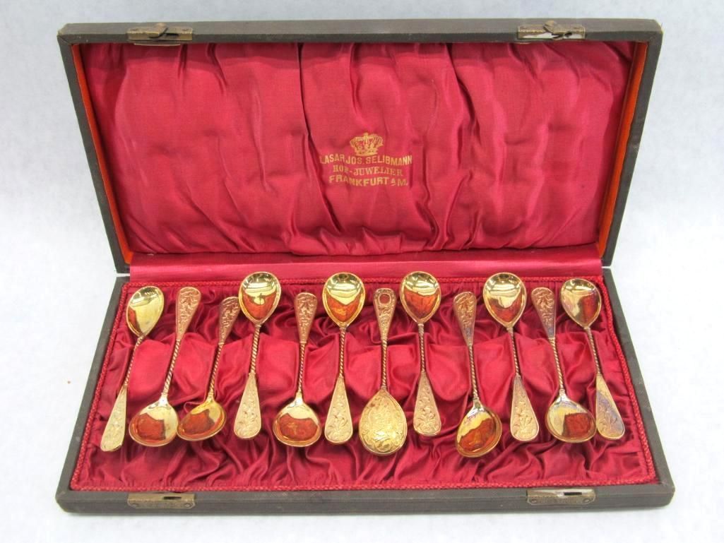 Set of gold-colored spoons in a lined, open wooden case.