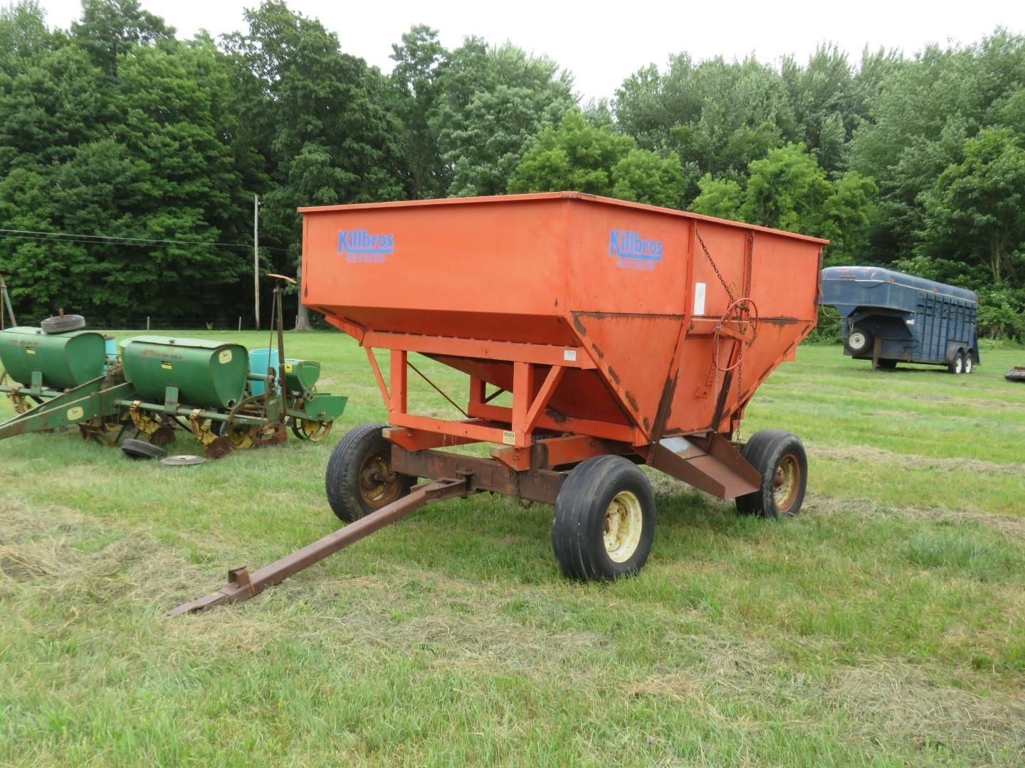 Orange farm spreader trailer in a grassy field.