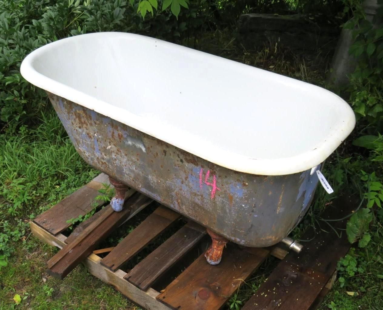 Claw-foot bathtub on a wooden pallet outdoors, white interior.
