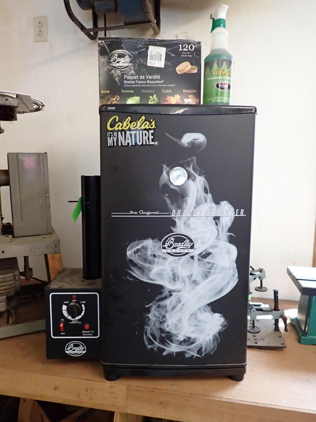 Black smoker with a temperature gauge, a control panel, and accessories on a wooden surface.