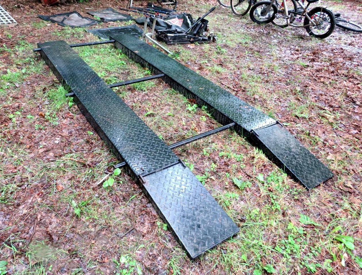 Black metal car ramps on ground, used for vehicle maintenance.
