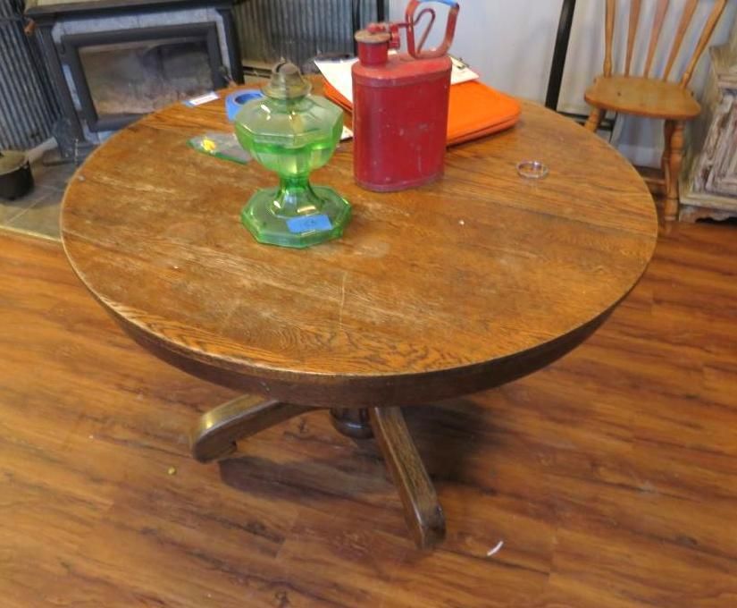 Round wooden table with objects, including a green glass lamp, and a red can.