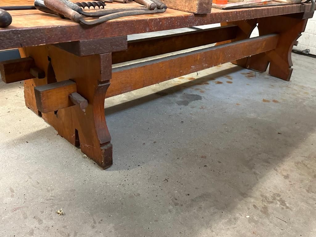 Wooden workbench with tools on top, sitting on a concrete floor.