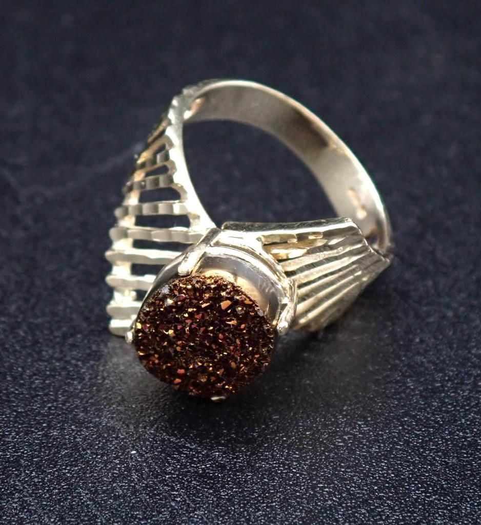 Silver ring with a brown, crystal-covered stone and a geometric design.