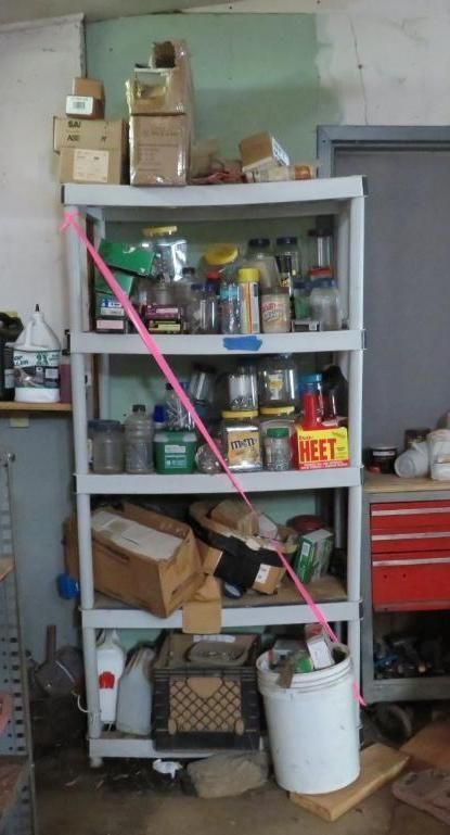 Plastic shelving unit in a garage, holding various items like jars, boxes, and containers. Pink ribbon is tied around it.