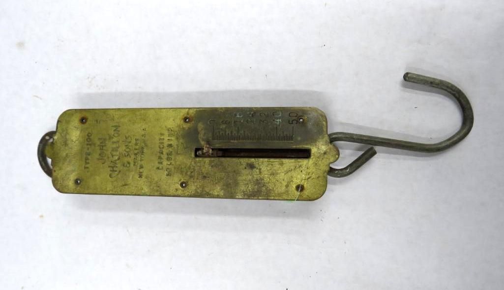 Brass spring scale with a hook and handle.