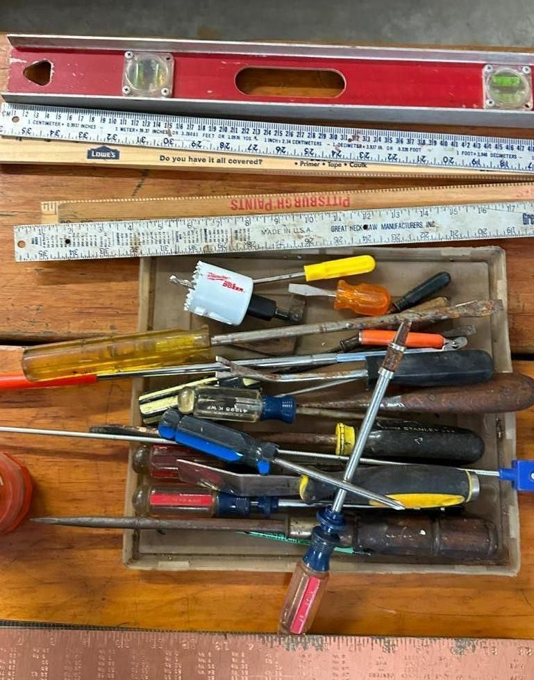 Tools: level, rulers, screwdrivers, and other hand tools arranged on a wooden surface.