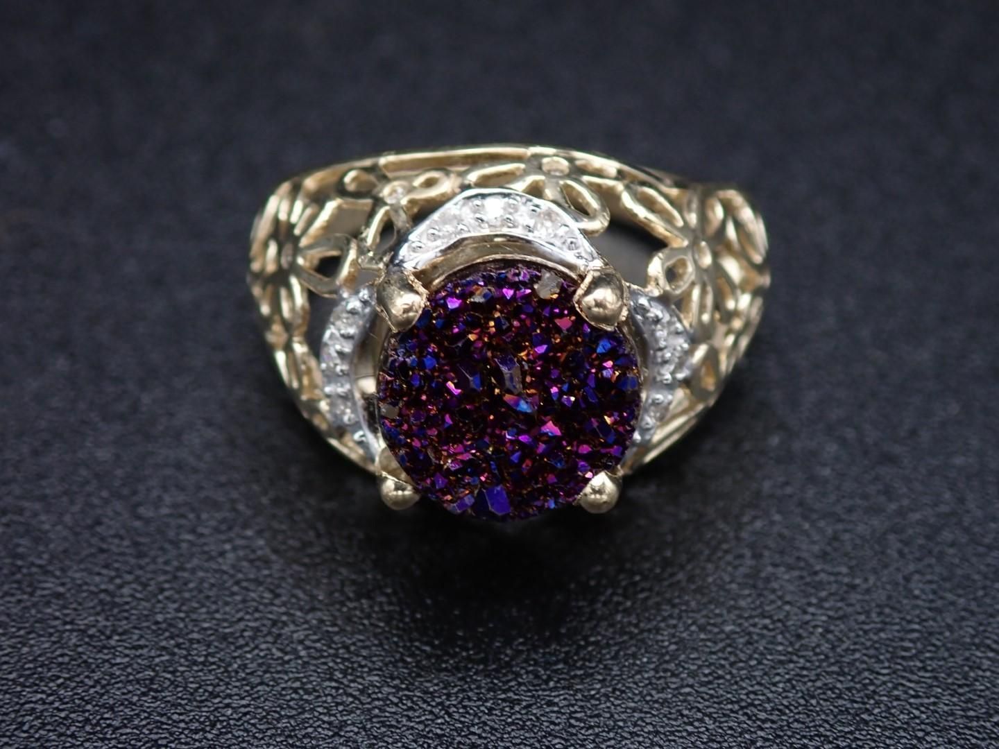 Gold ring with a large, purple druzy stone and diamond accents.