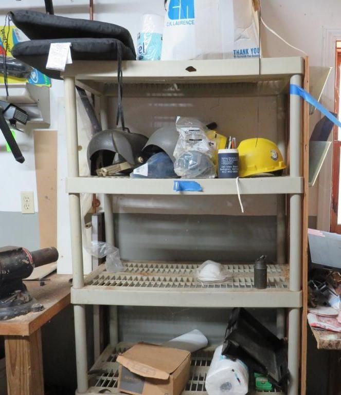 Plastic shelving unit holding safety equipment: helmets, masks, and supplies. Beige and grey tones.