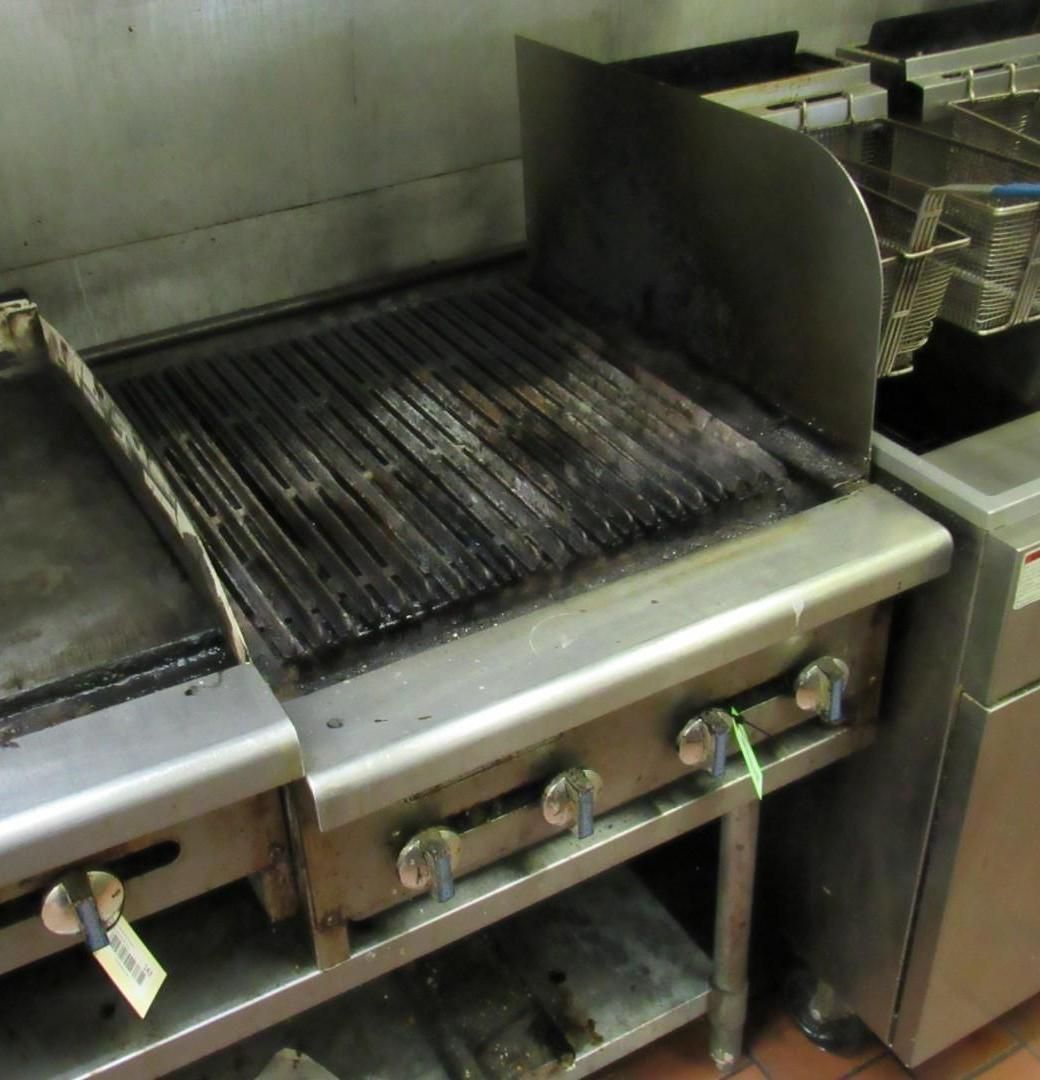 Commercial grill with grates, stainless steel. In a kitchen setting.