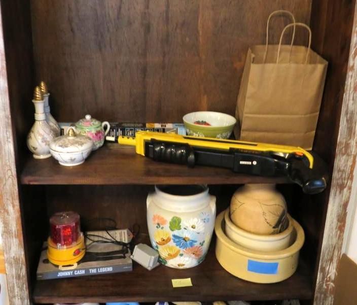 Wooden shelf with various items, including jars, a paper bag, and a yellow and black tool.