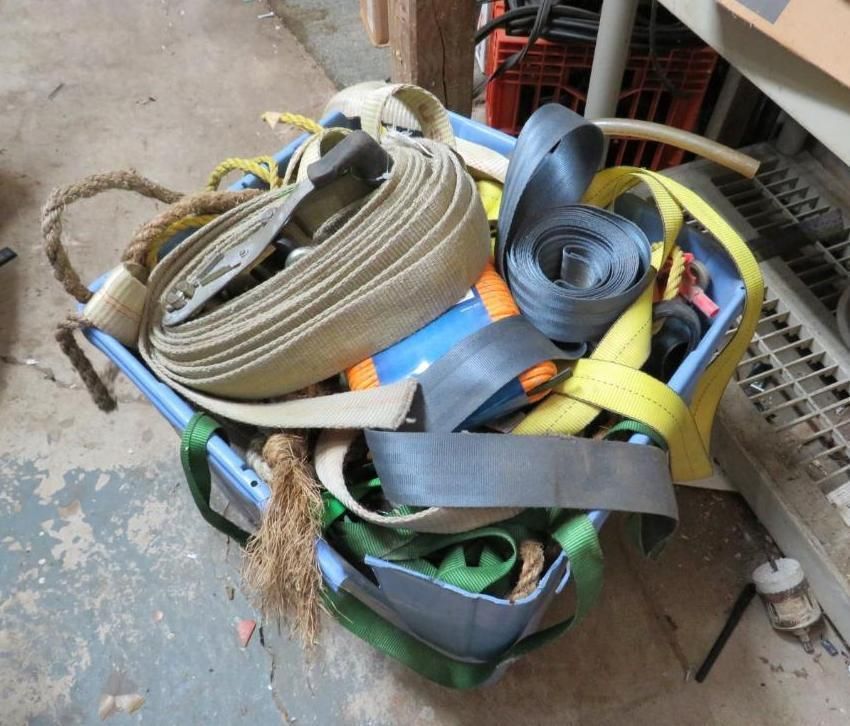 A blue bin overflowing with coiled, colorful straps, ropes, and cargo tie-downs.
