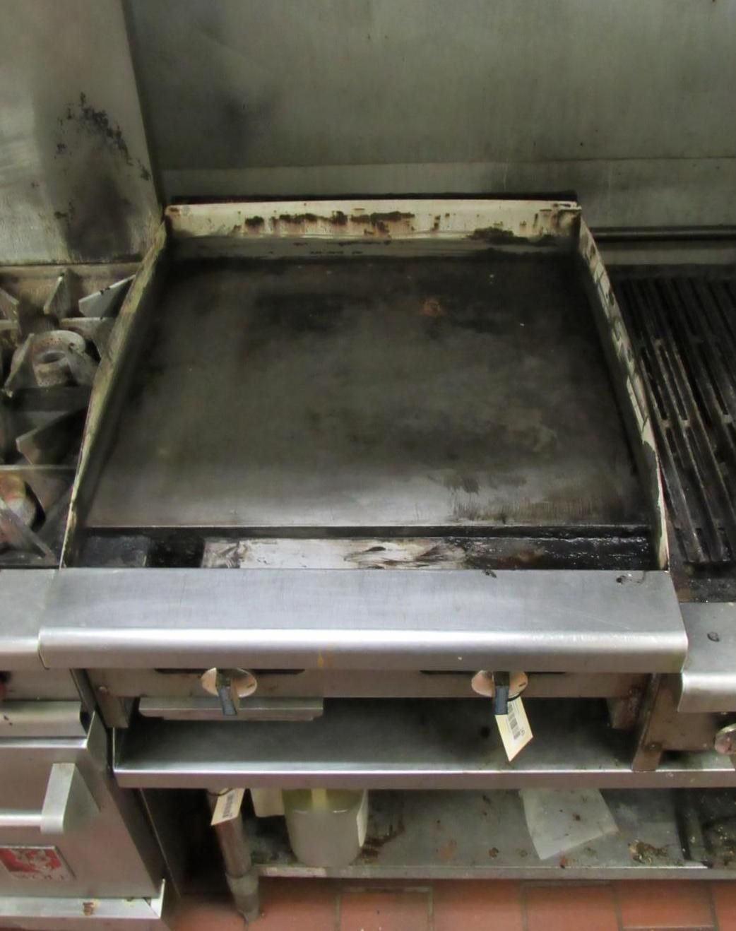 An industrial flat-top griddle in a commercial kitchen setting.