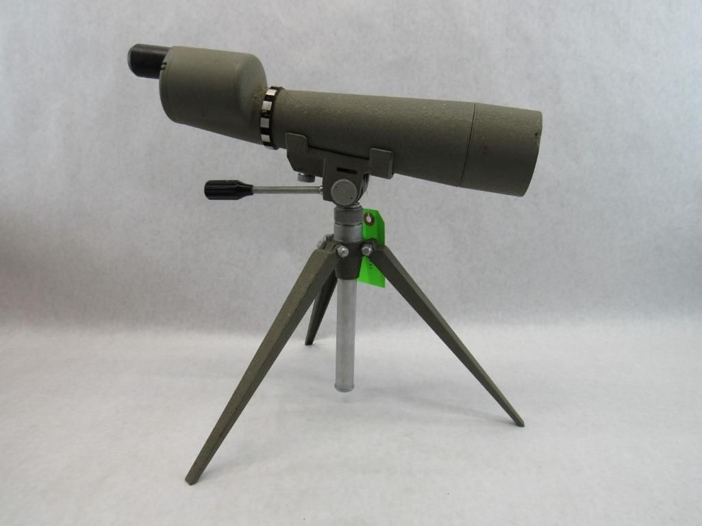 Olive green spotting scope on a tripod, set against a plain background.