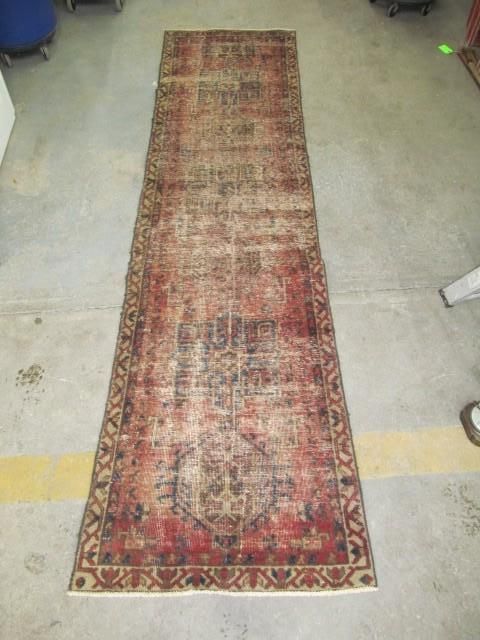 Red and brown patterned runner rug on a concrete floor.