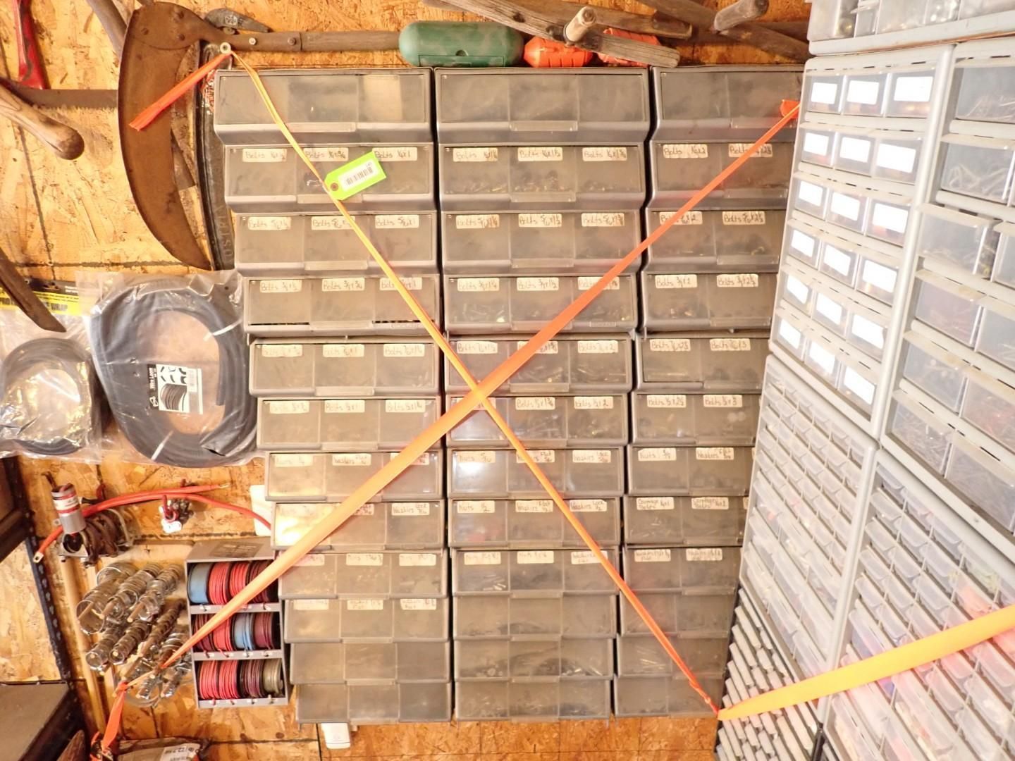 Workshop storage wall with rows of small parts drawers, crossed by orange tape in an X.