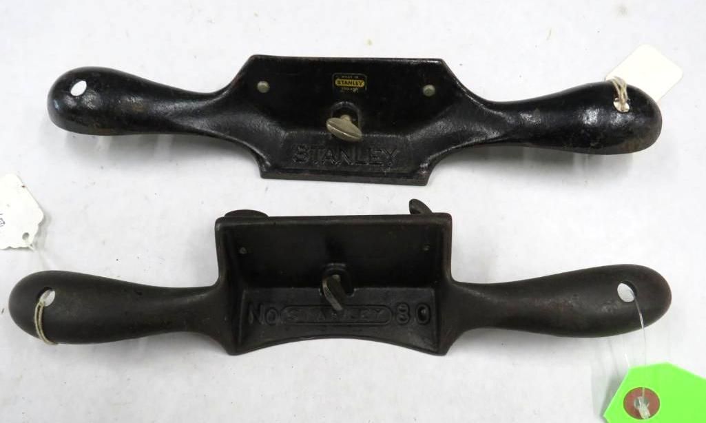 Two black drawshaves, woodworking tools, with handles, displayed.