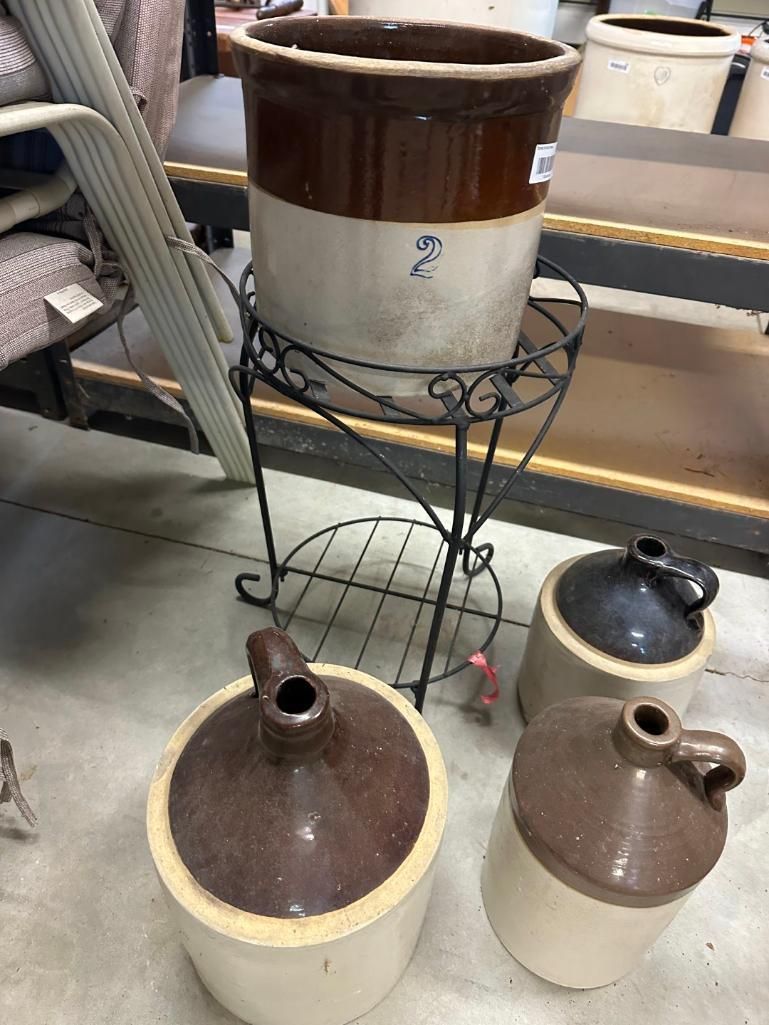 Antique stoneware pots and jugs on a metal plant stand in a workshop.