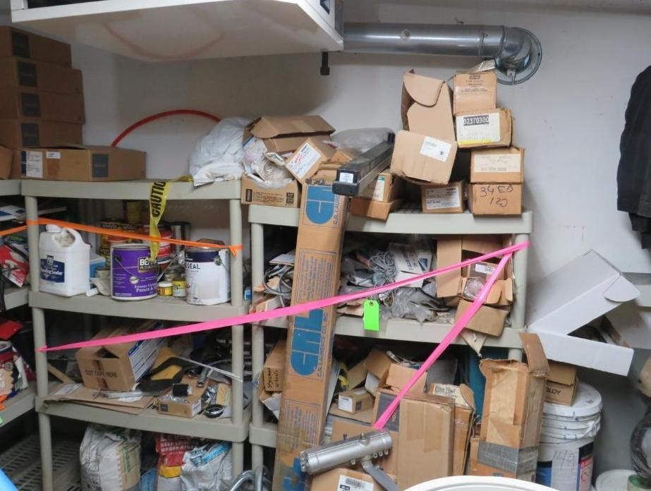 Storage shelves in a basement with boxes, supplies, and pink caution tape.