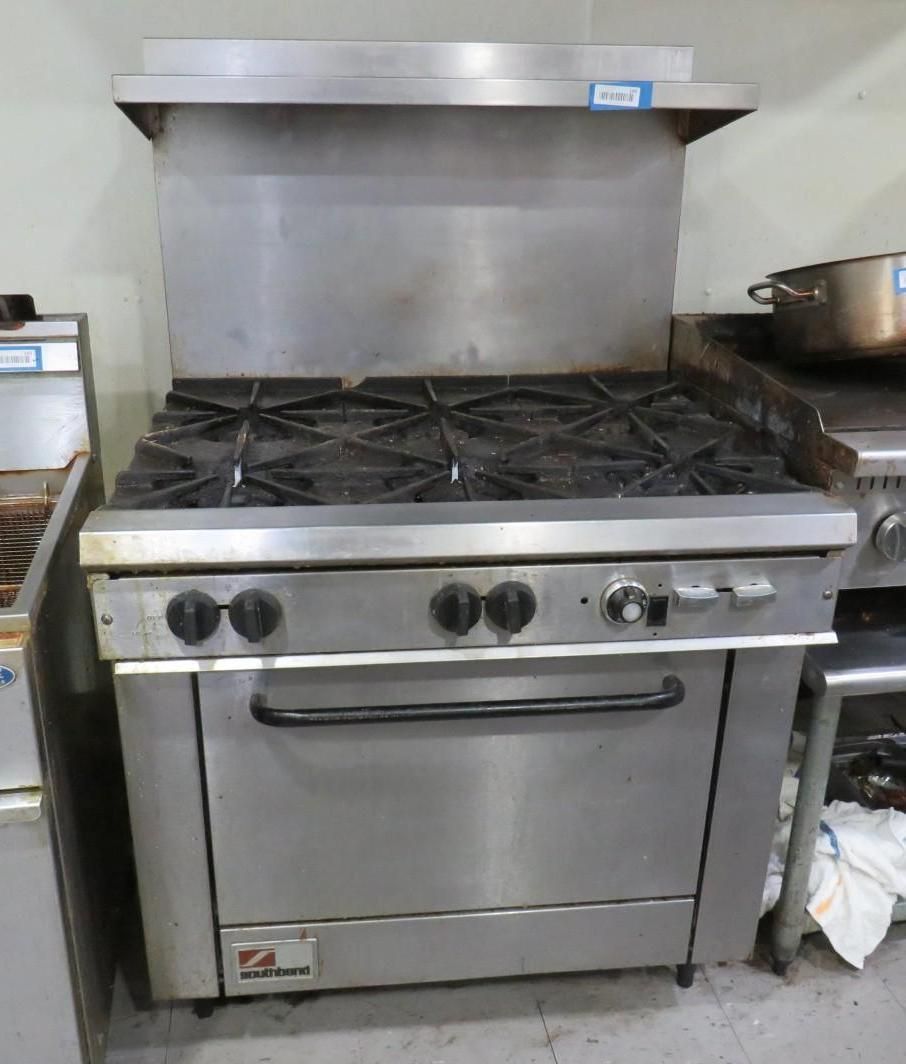 Commercial stainless steel gas range with six burners and oven.