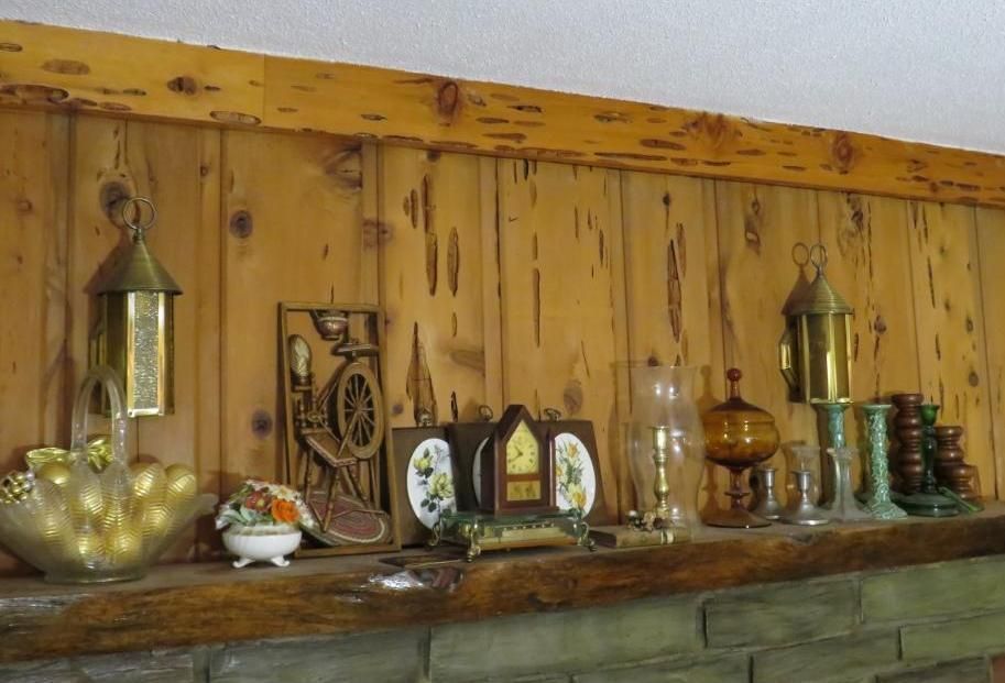 Shelf with decorative items against a wood-paneled wall. Items include lanterns, clock, vase, and figurines.