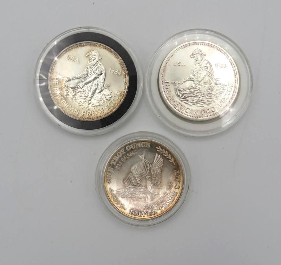 Three silver coins in protective cases, each depicting a seated figure in a landscape.