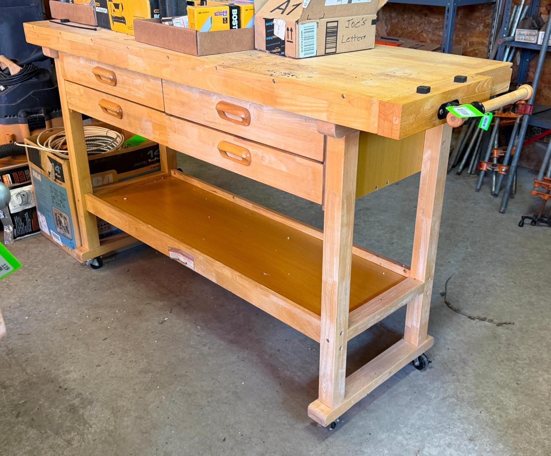 Wooden workbench with drawers and lower shelf in a workshop, on casters