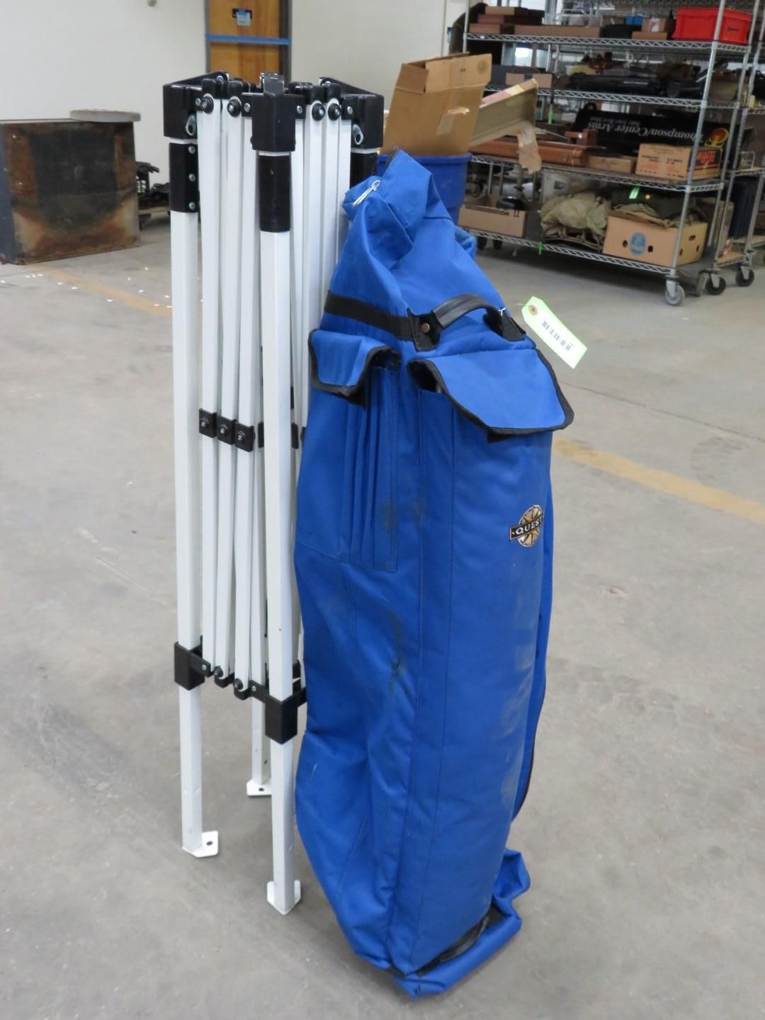 White folding tent frame next to a blue carry bag.