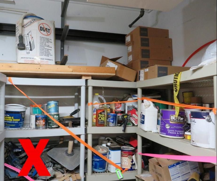 Storage shelves with paint cans, tools, and boxes. Straps secure items. Garage setting.