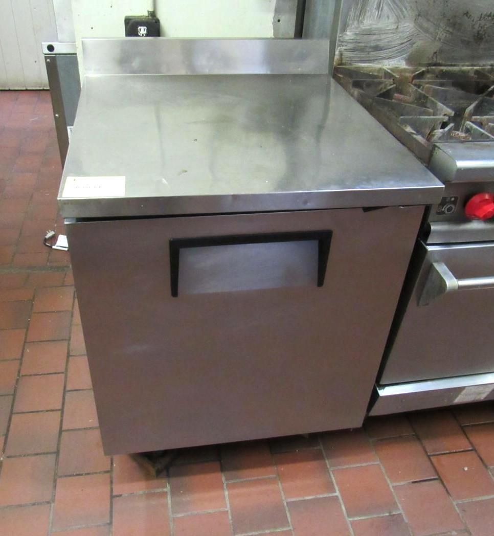 Stainless steel refrigerator next to a commercial gas range.