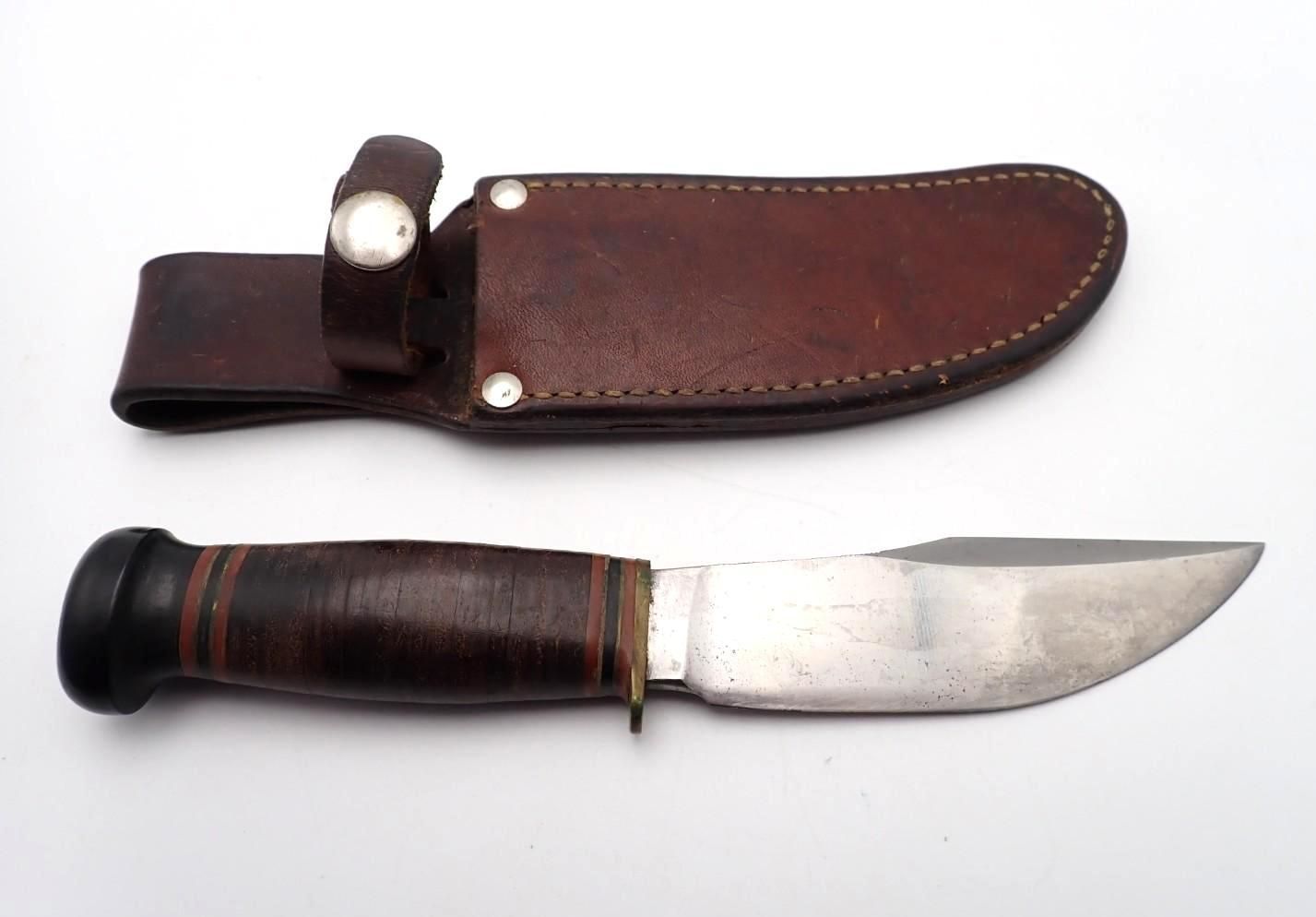 Brown leather sheath and wooden-handled knife laid side by side on a white background