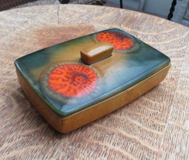 Ceramic box with orange circular designs on a green and tan glazed lid.