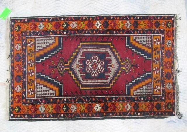 Small rectangular rug with red, orange, and navy geometric designs.