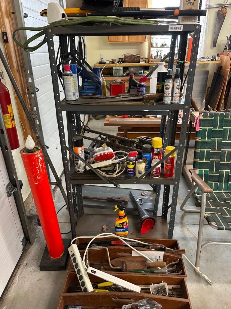 Metal shelving unit with tools, cans, and other items in a garage.