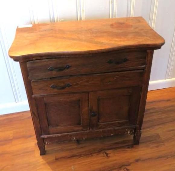 Wooden antique cabinet with two drawers and two doors, set on a wood floor.