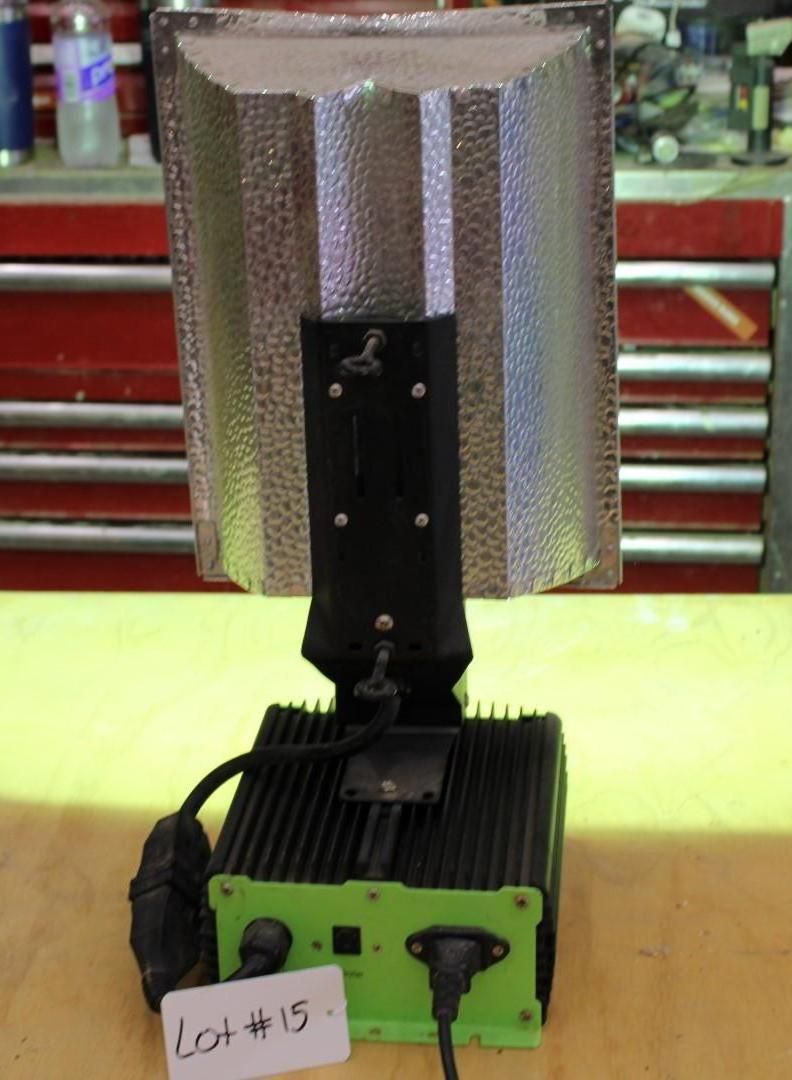 A grow light with a silver reflector and a green and black ballast.