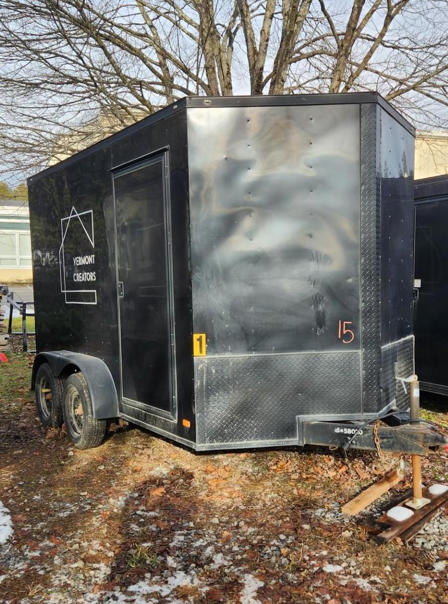 Black cargo trailer with a door, parked outdoors.