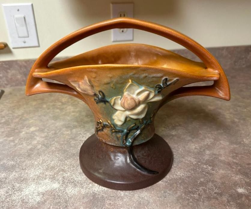 Ceramic basket vase with handle. Floral design in shades of orange, green, and brown on a brown base.