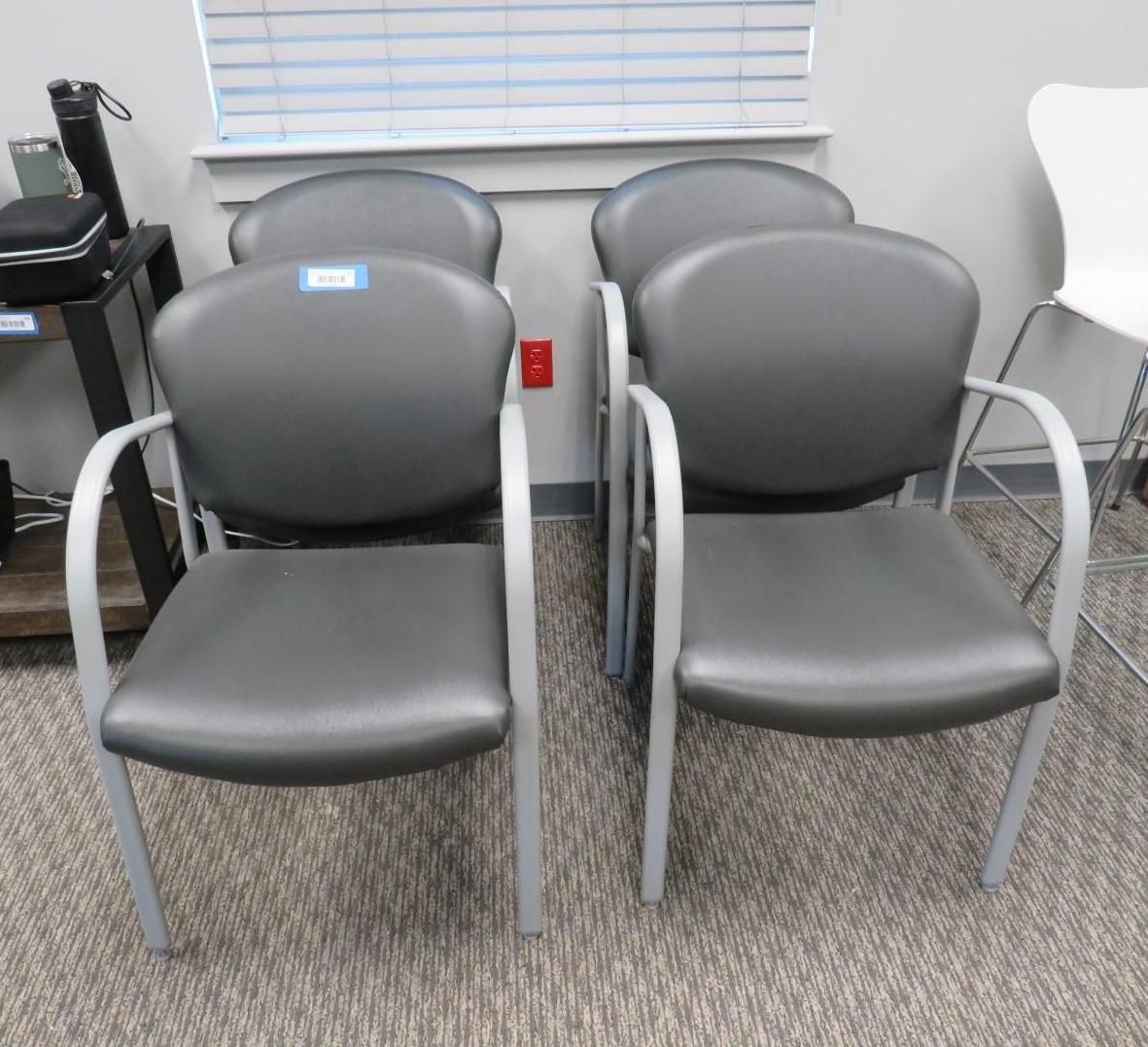 Four gray chairs with silver frames in an office.