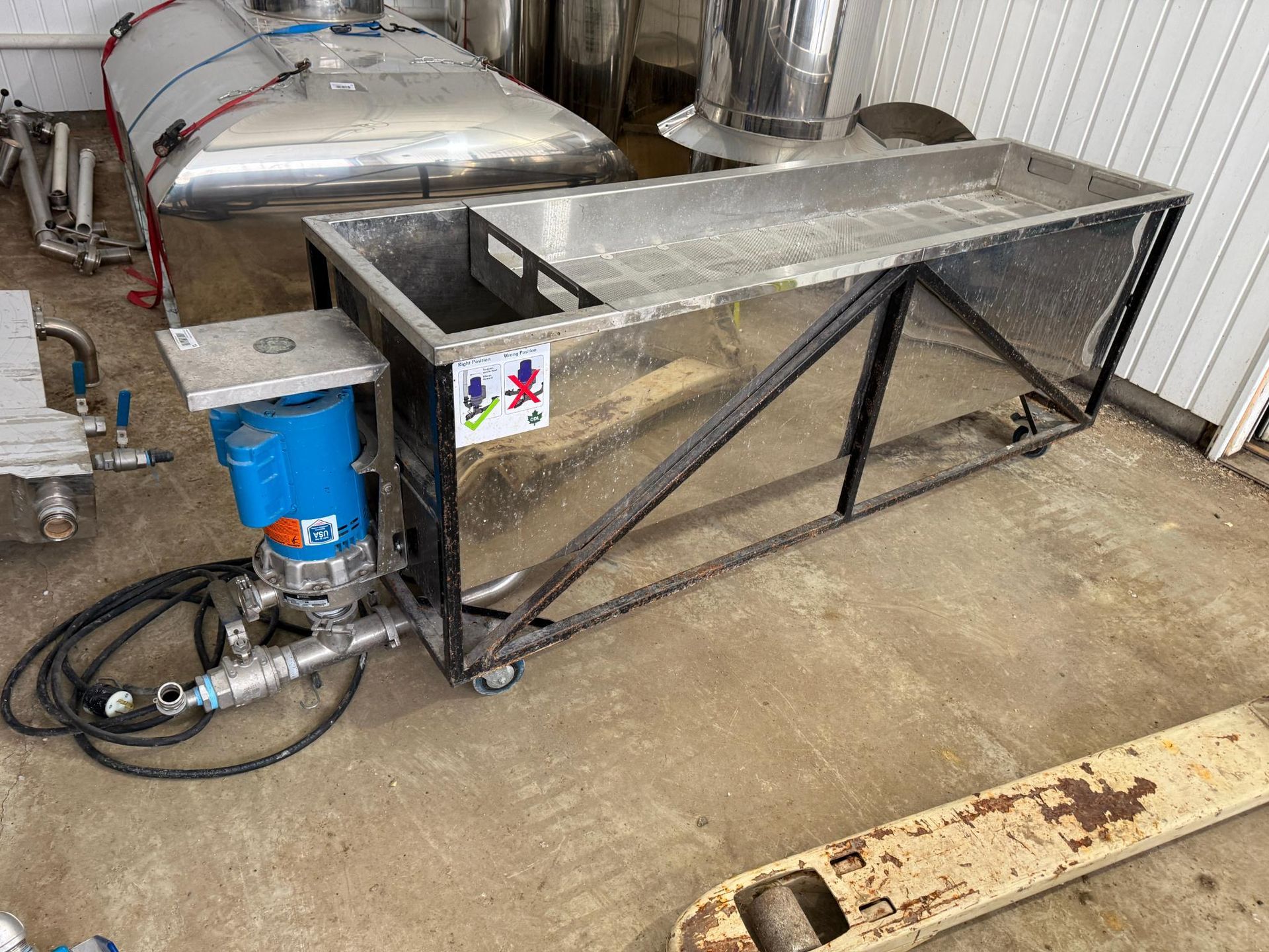 Stainless steel industrial processing equipment with a pump and tank on wheels.