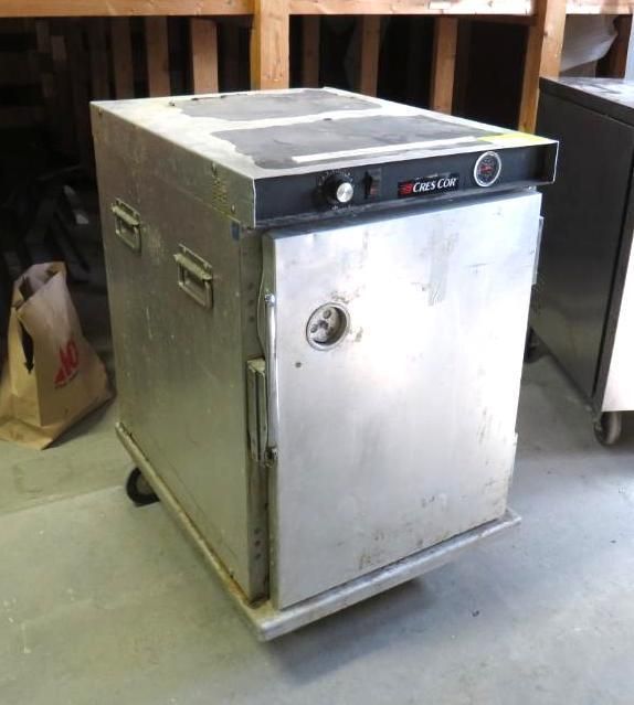 Stainless steel commercial food warmer with a black control panel and door on wheels.