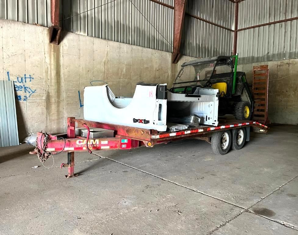 A utility trailer with a white Jeep bed and a green utility vehicle inside a metal building.