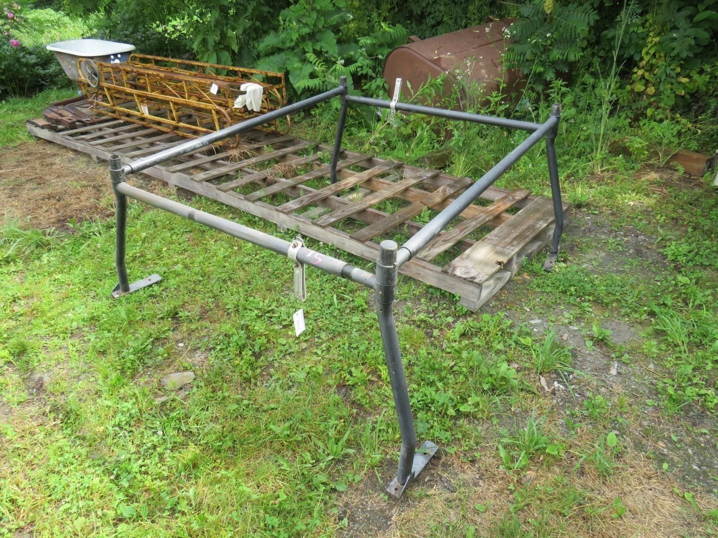 Black metal truck bed rack on grassy ground.