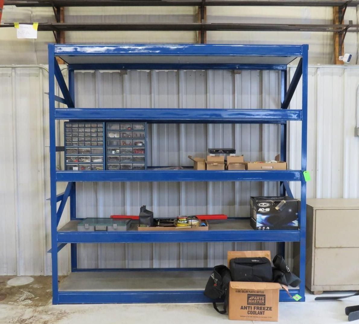 Blue metal shelving unit with supplies in a workshop setting.